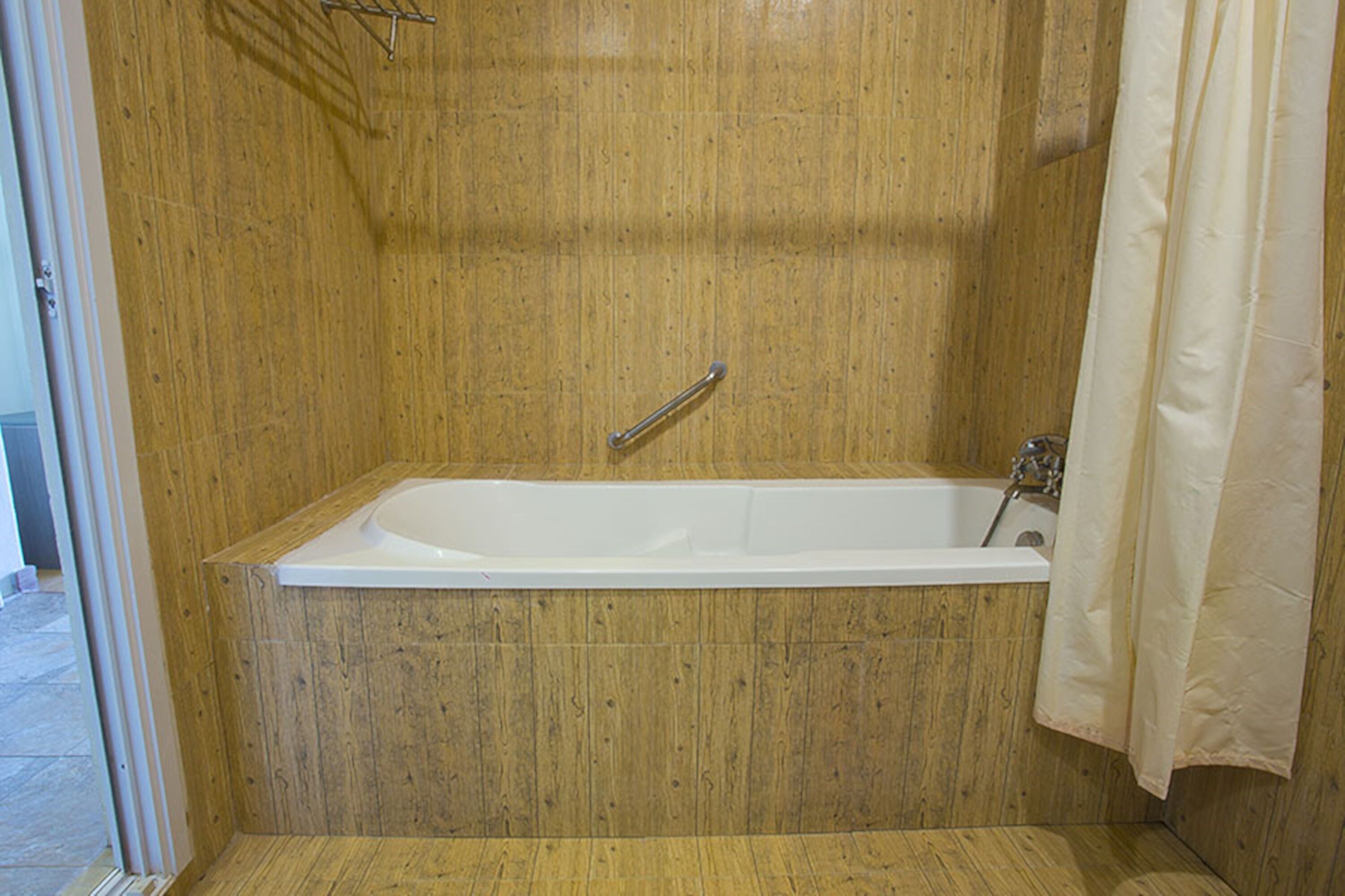 A bathroom with a wooden wall, a white bathtub, and a shower curtain.