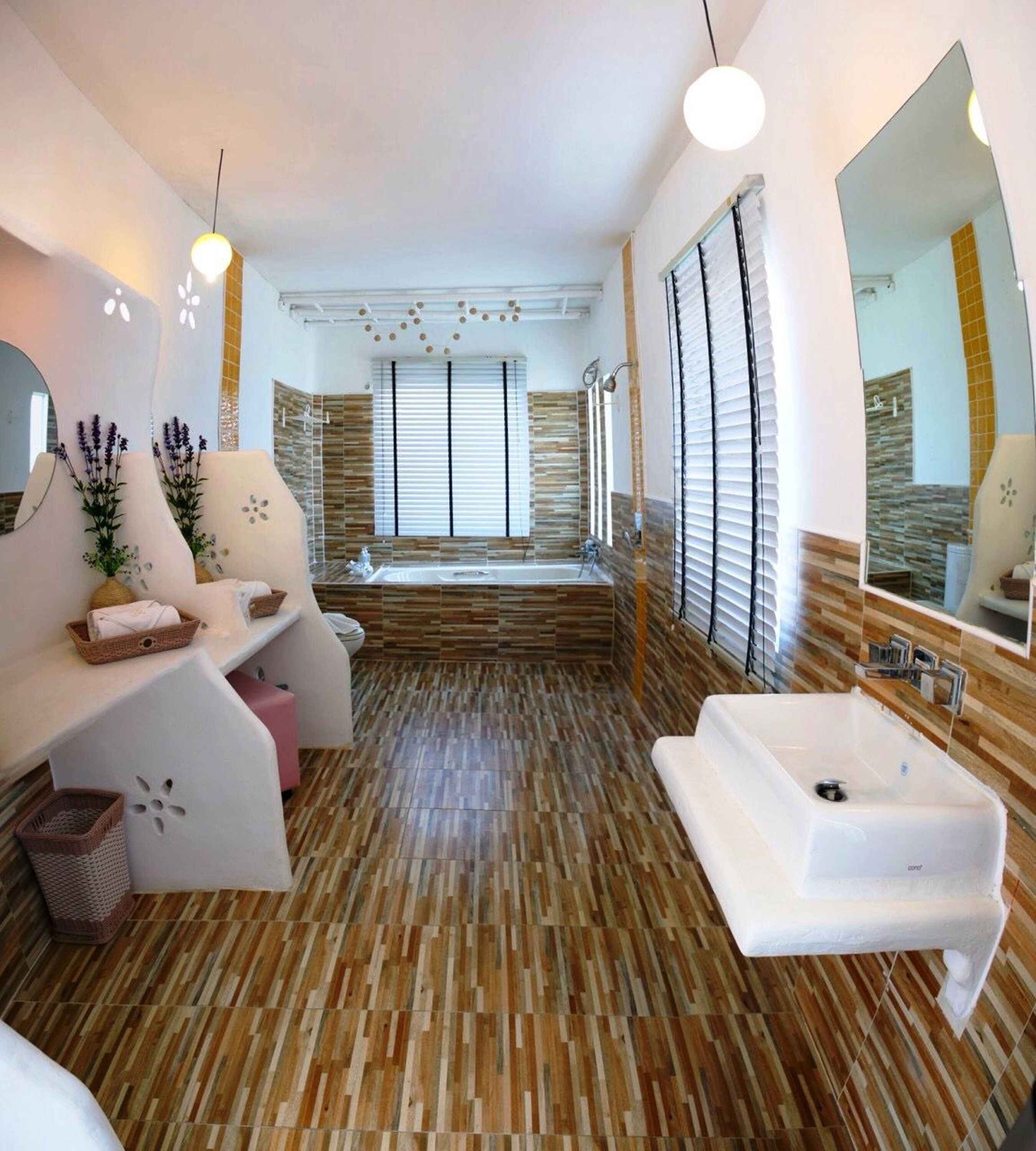 Ein modernes Badezimmer mit einer großen Badewanne, einem weißen Waschbecken und einer Sitzecke mit einer Bank und Kissen.