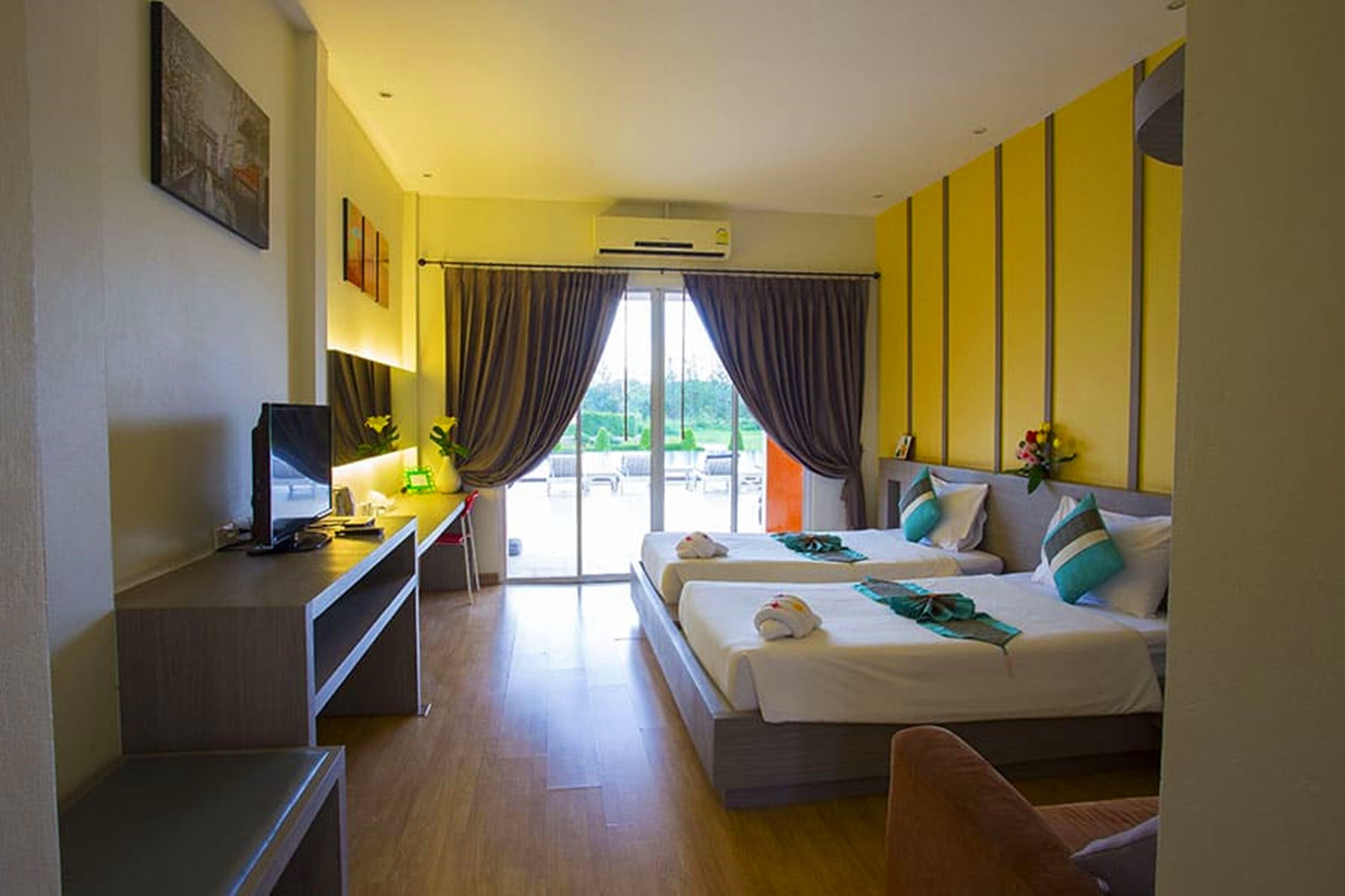 Camera d'albergo con due letti, una scrivania con un computer, una sedia e vista sull'esterno.