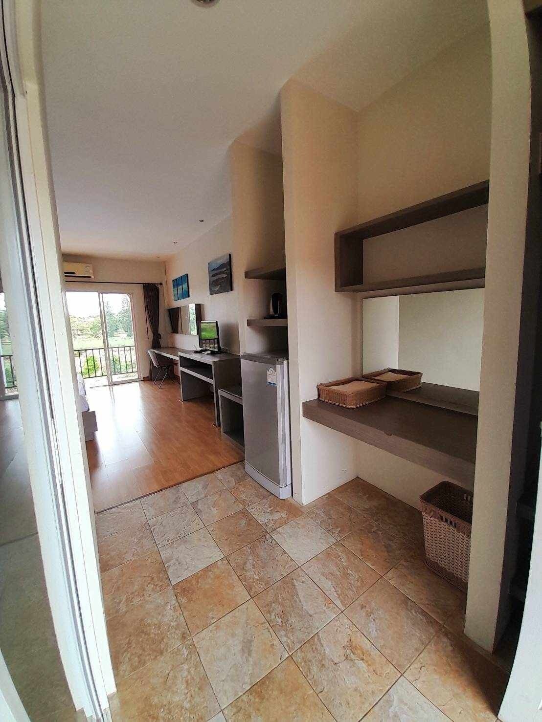 A spacious kitchen with a refrigerator, a dining table, and a TV mounted on the wall.