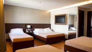 Habitación de hotel con dos camas individuales, una mesita de noche con teléfono, un televisor montado en la pared y un espejo.