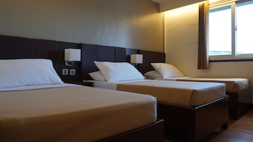A hotel room with two beds, a large window with curtains, and a wall-mounted lamp.