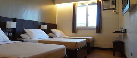 Habitación de hotel con dos camas, una ventana con cortinas, un taburete pequeño y un estante con botellas de agua.