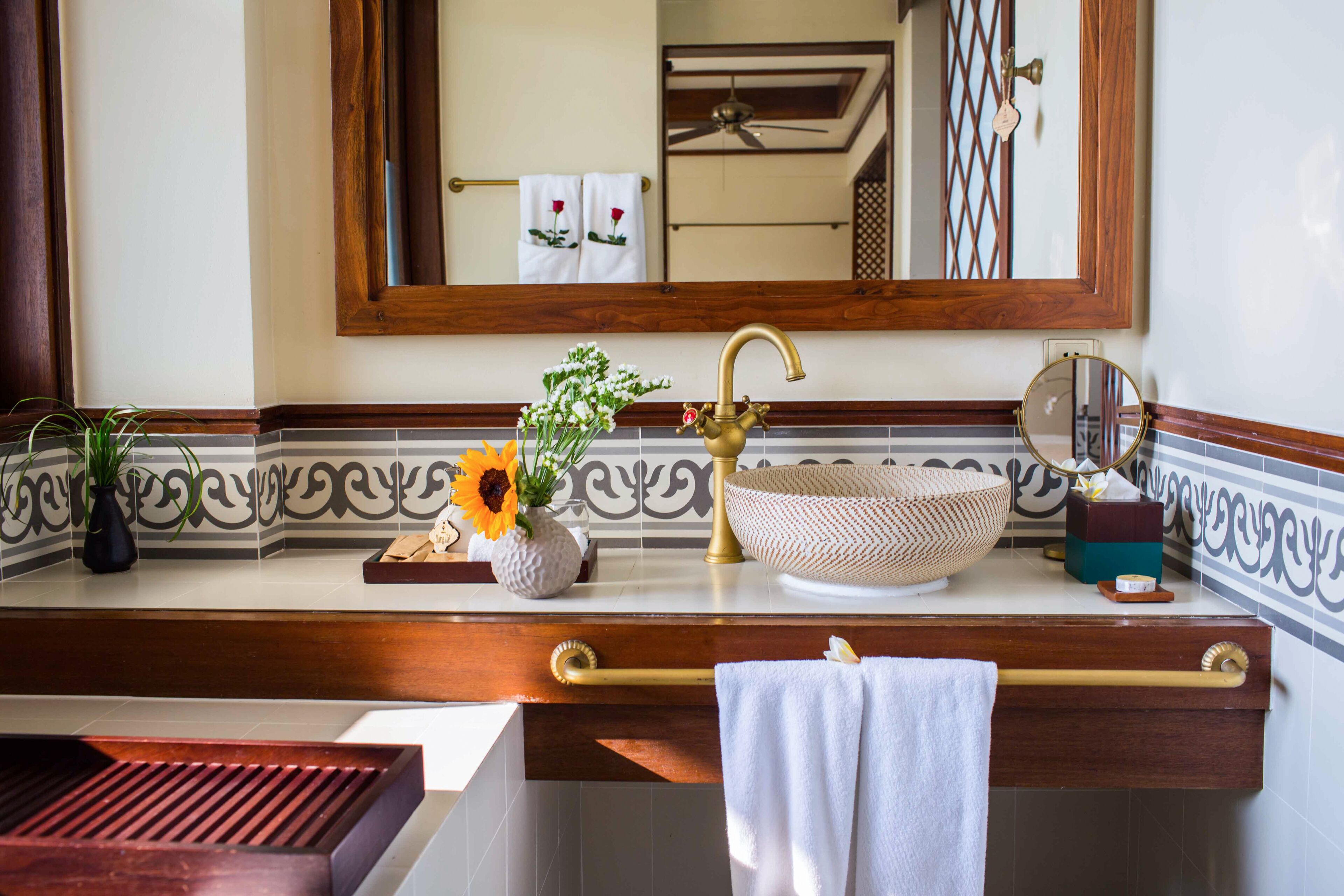 A bathroom with a wooden vanity, a sink with a decorative bowl, a mirror, and a towel rack.