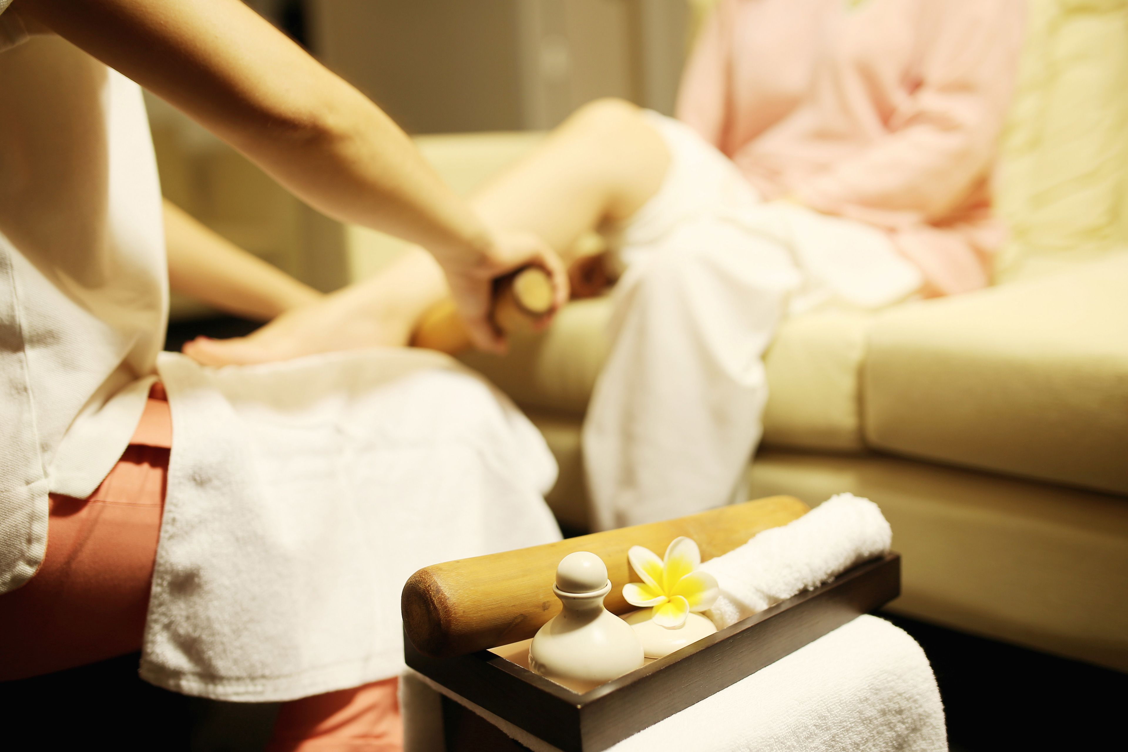 A person receiving a manicure, with a tray of toiletries and a towel on a wooden table.