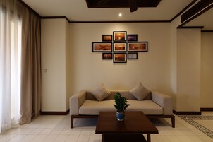 A living room with a sofa, a coffee table with a plant, and a wall with framed pictures.