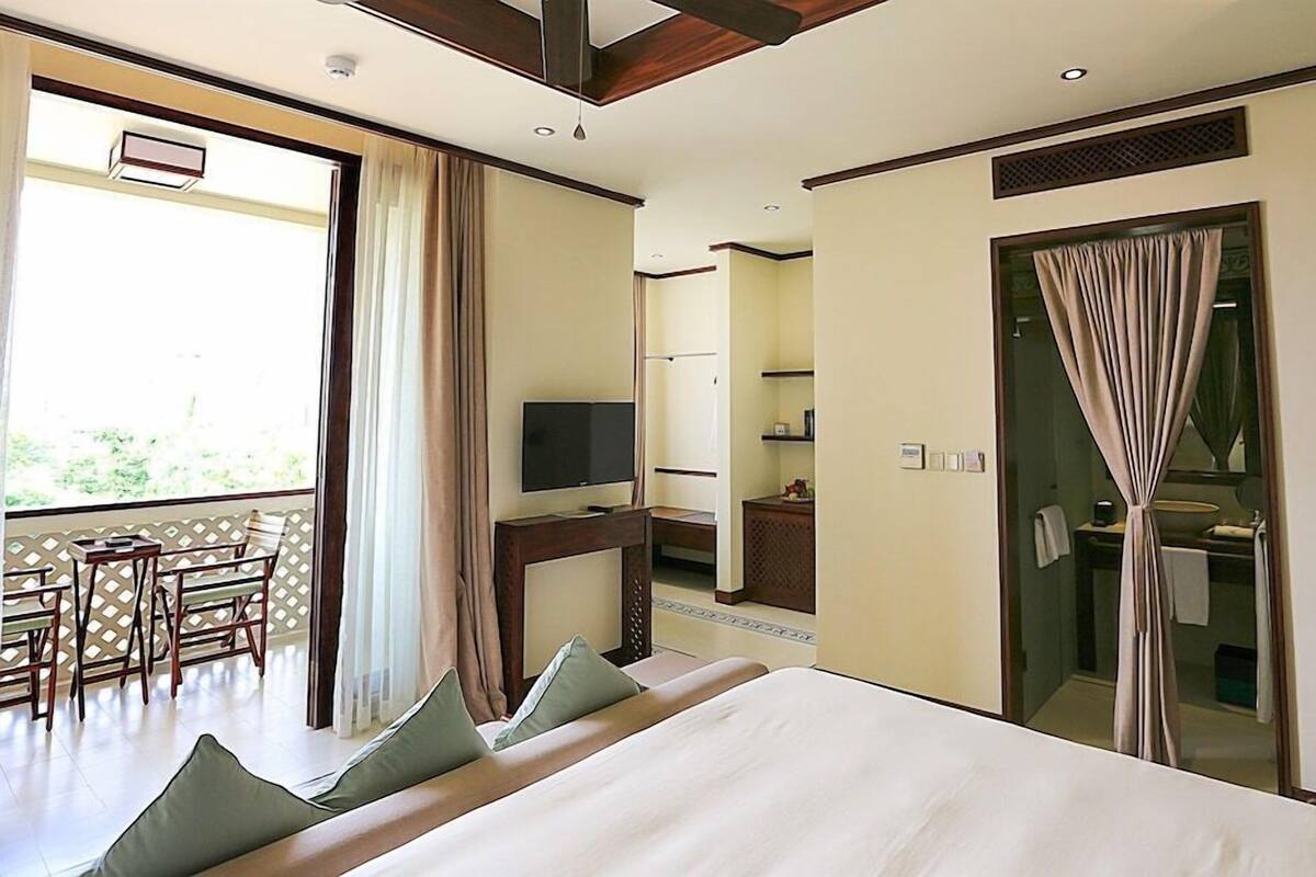 Habitació d'hotel amb un llit, una televisió, escriptori i un balcó.