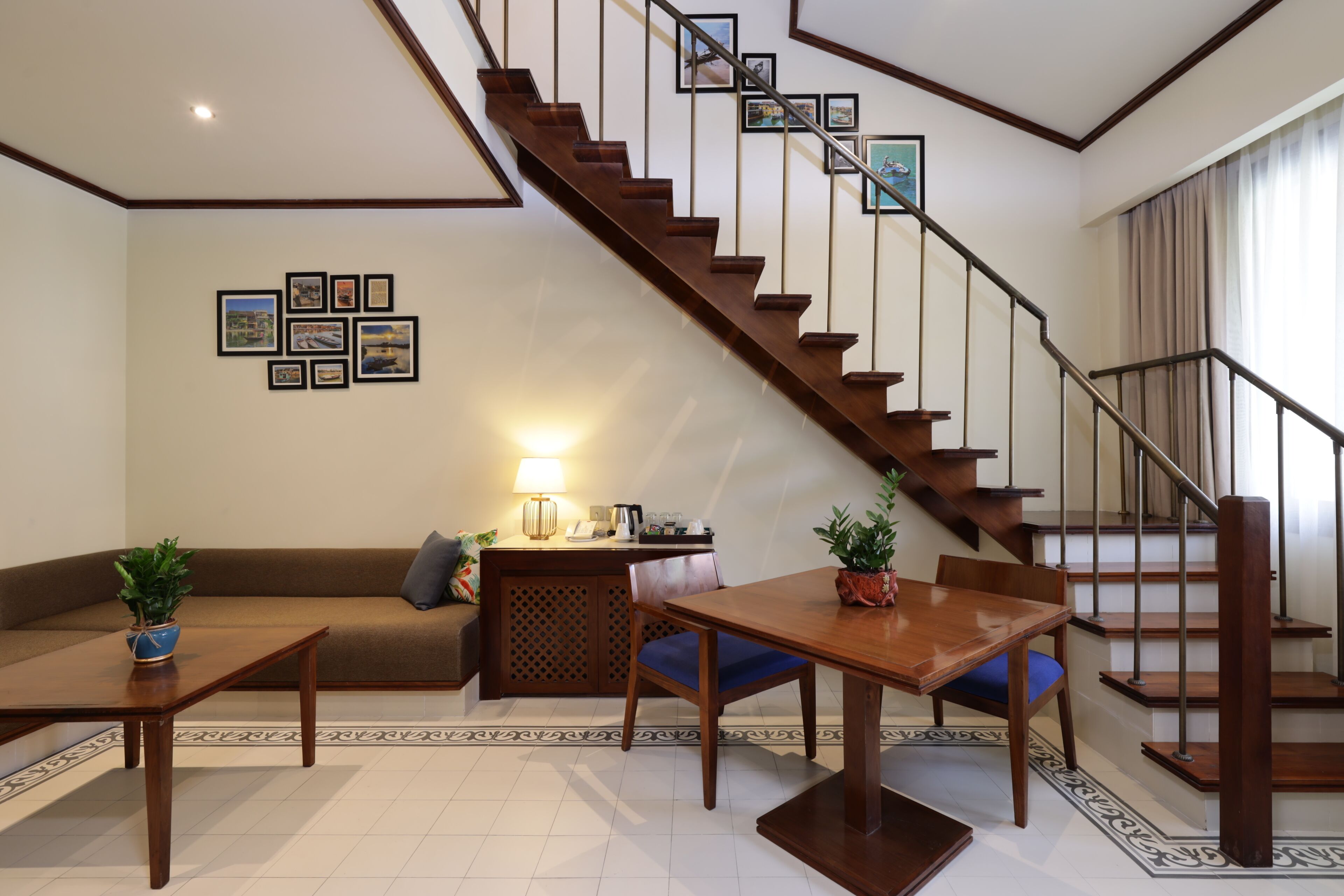 A modern living room with a wooden staircase, a sofa, a dining table, and a coffee table.
