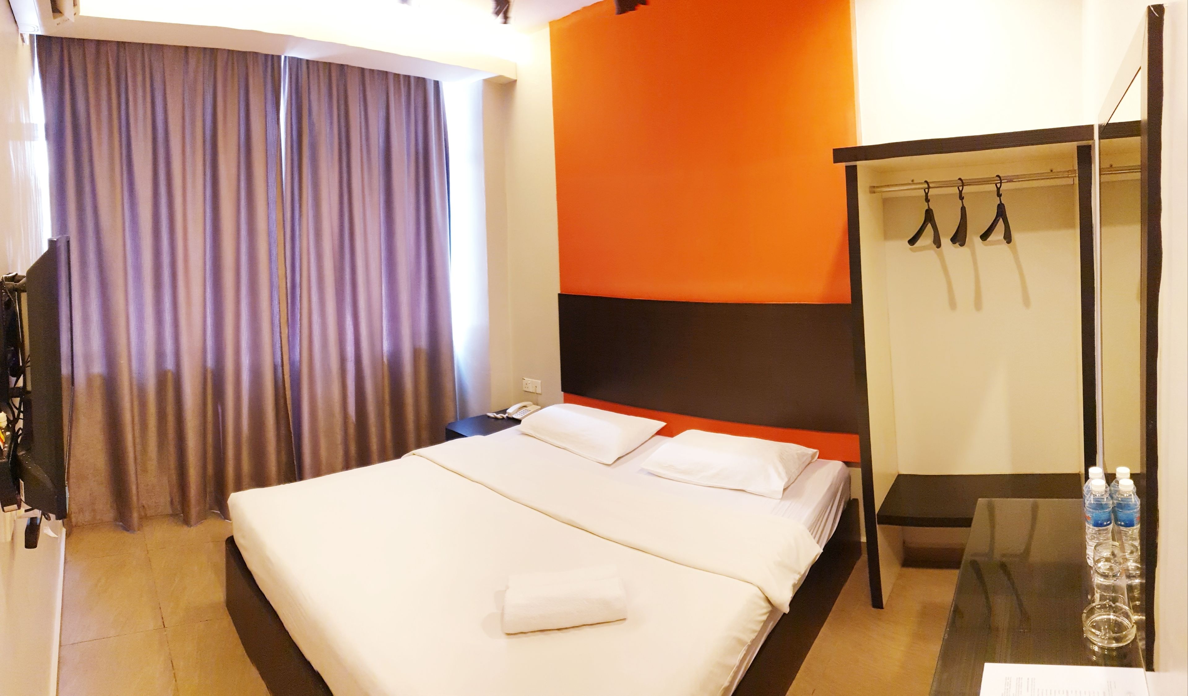 Une chambre d’hôtel avec un grand lit, un bureau, une armoire et un rideau.