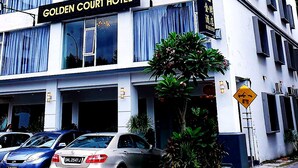 Um hotel com vários andares e uma placa que diz 'Golden Court Hotel'.