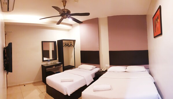 A hotel room with two beds, a ceiling fan, a mirror, a dresser, and a TV. - Golden Court Hotel (Johor Bahru)