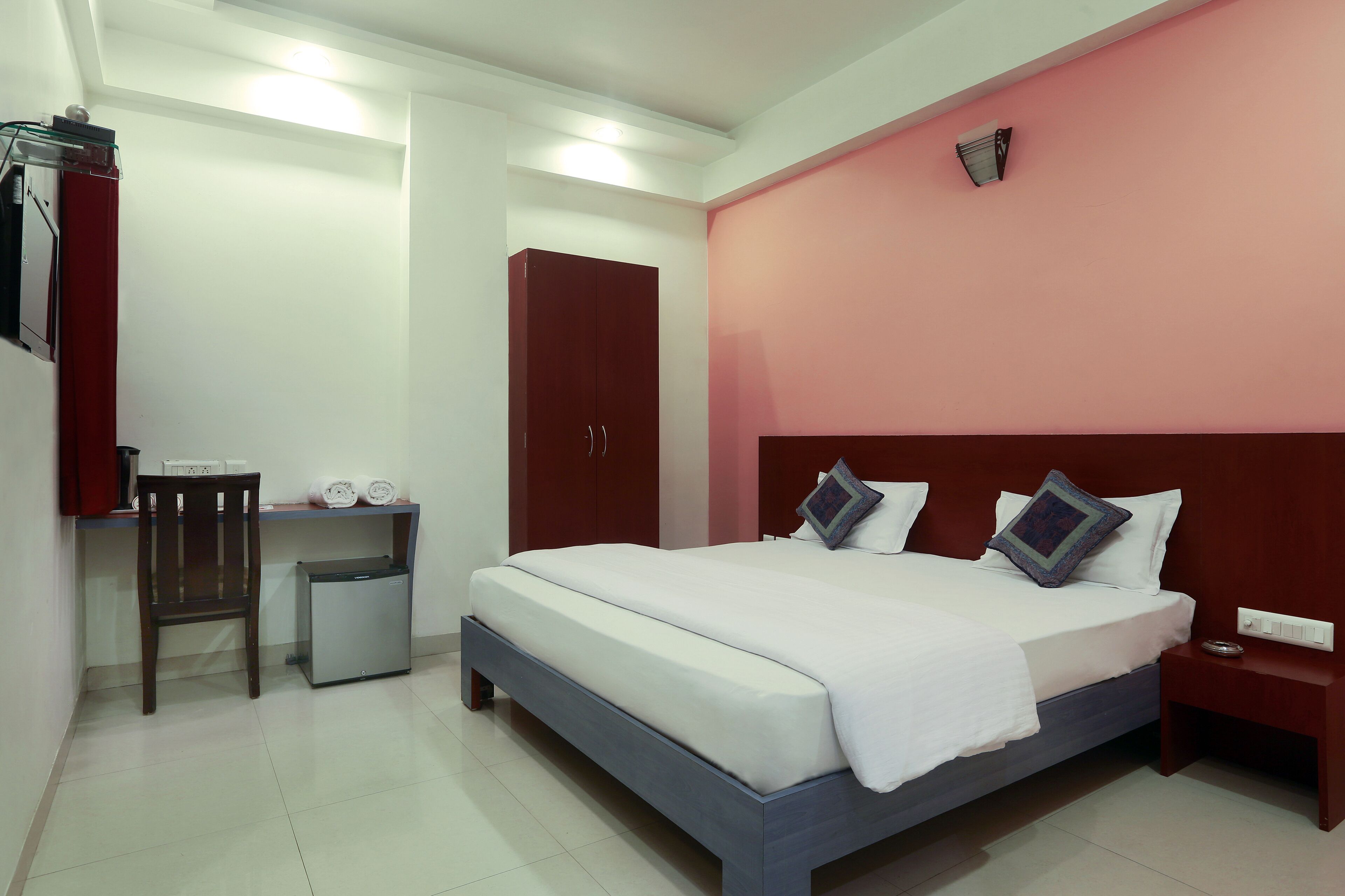 A neatly arranged bedroom with a bed, a desk, a chair, and a wardrobe.