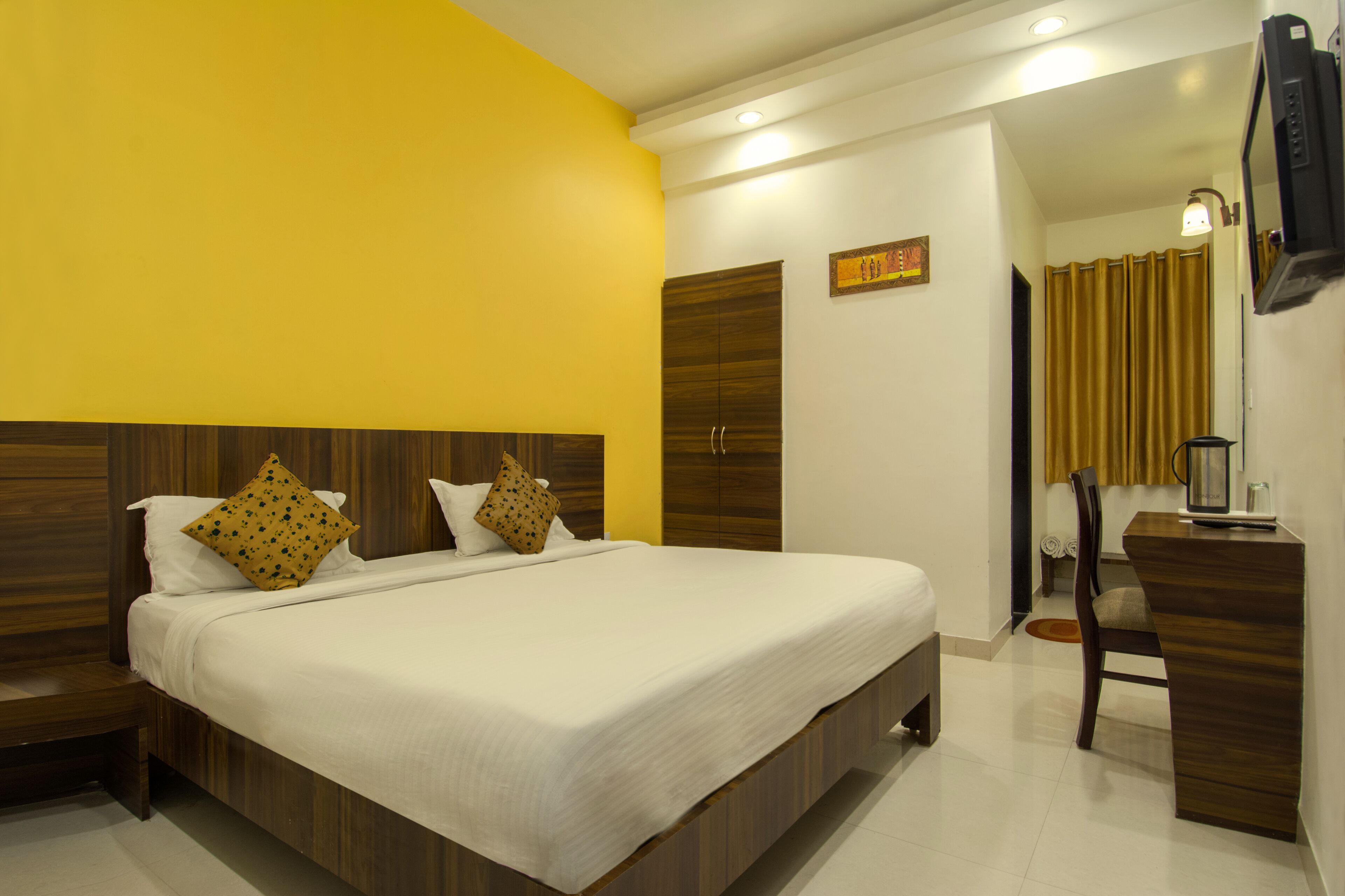 A hotel room with a large bed, wooden headboard, and a desk with a chair.