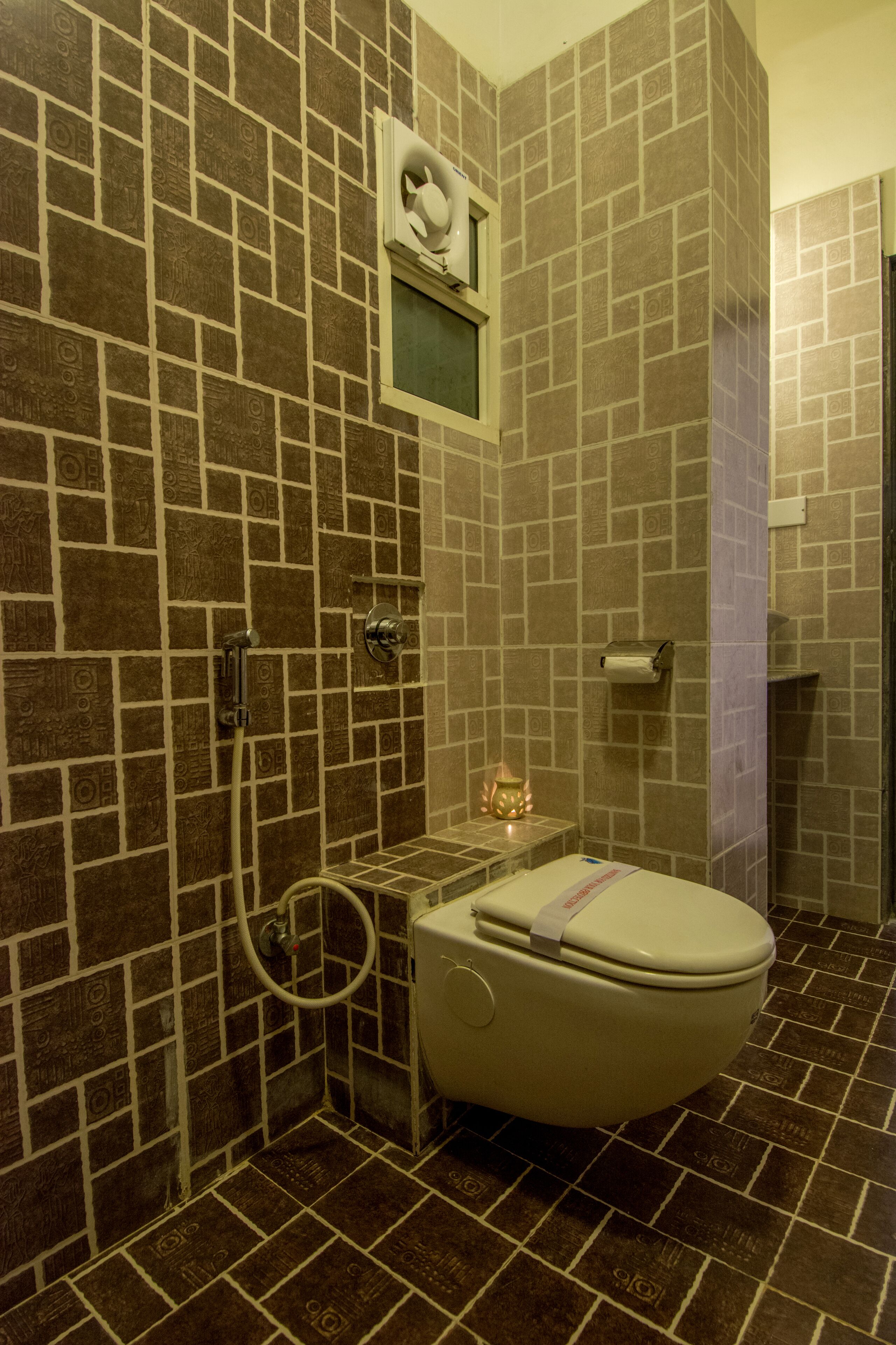 Une salle de bain avec des toilettes, une douche et une petite fenêtre.