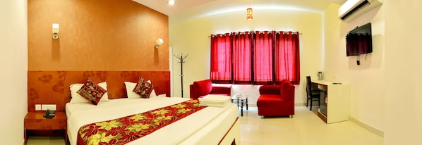 A hotel room with a bed, a desk, a chair, a table, and a TV. - Hotel Metropolitan Near Sindhi Camp (Jaipur)