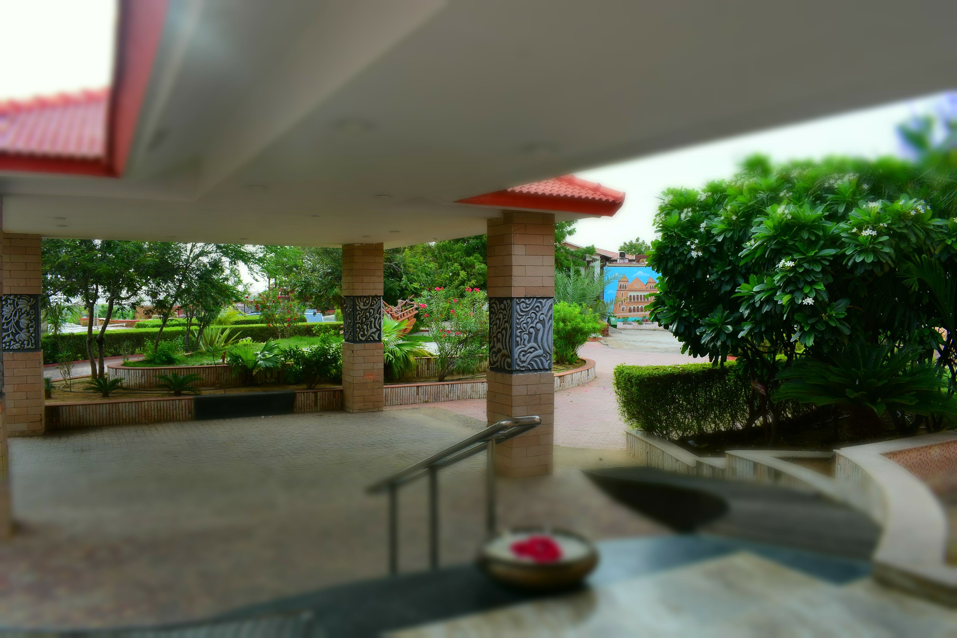 Un espacio al aire libre techado con piso de baldosas, barandilla y un cuenco con un objeto rojo.