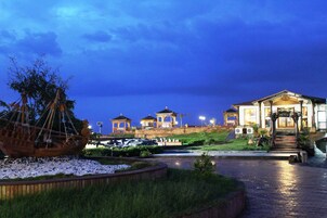 A waterfront property with a large boat, multiple gazebos, and a well-lit building.