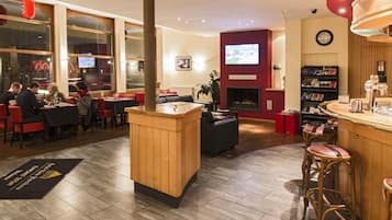 A restaurant with a bar area, seating, and a fireplace.
