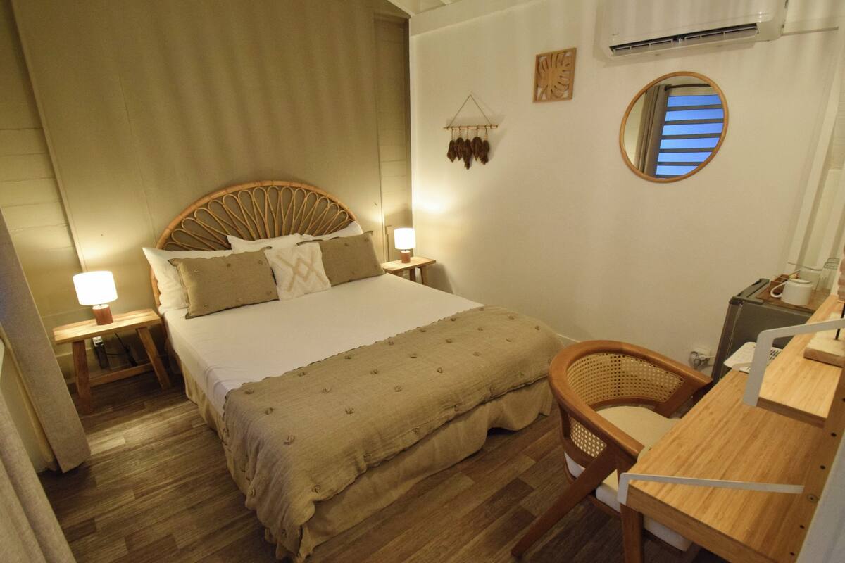 A neatly arranged bedroom with a bed, bedside tables, a chair, and a desk.