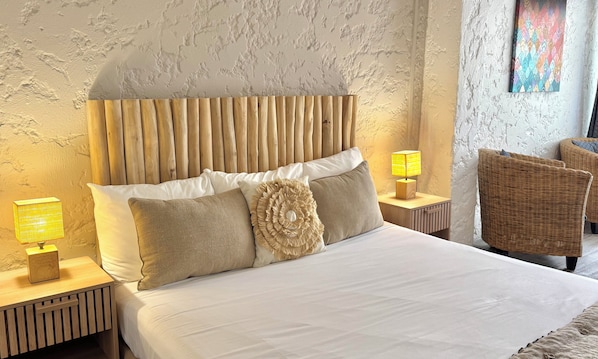 A neatly made bed with a wooden headboard, two bedside lamps, and a decorative pillow.