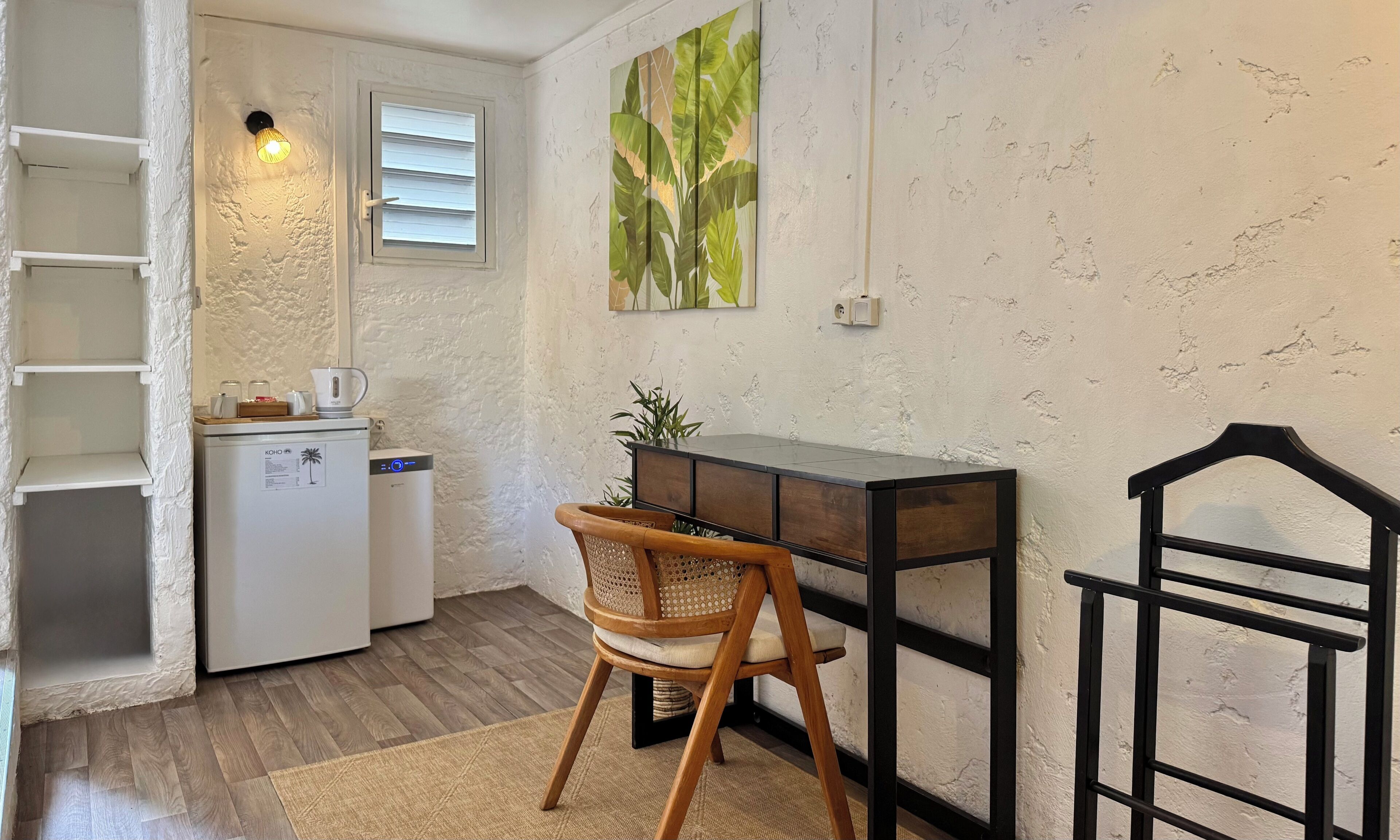 Une cuisine compacte équipée d’un réfrigérateur, d’une machine à café et d’une petite table à manger avec une chaise.