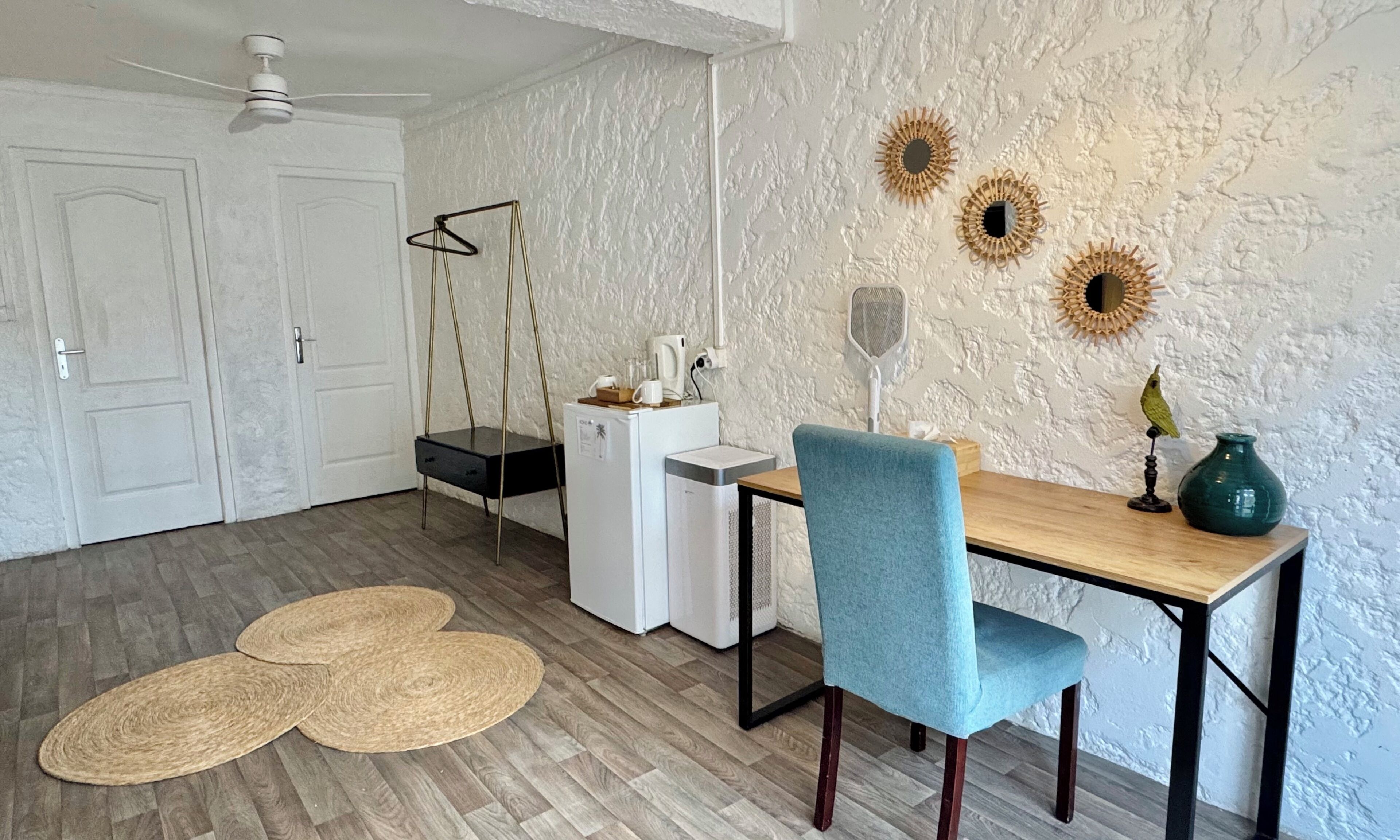 Un espacio de comedor compacto con una mesa de madera, una silla azul y un refrigerador blanco.
