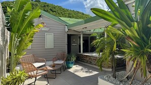 A patio area with wicker chairs and a table, surrounded by various plants and a small water feature. - KOHO-SXM (Grand Case)