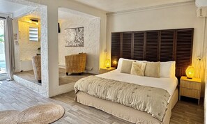 A spacious bedroom with a large bed, a wicker chair, and a view of the outdoors.