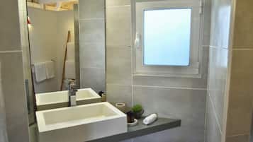 Un bagno moderno con due lavabi, un ampio specchio e una piccola finestra.