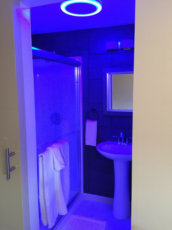 A bathroom with a shower, a sink, and a towel rack.