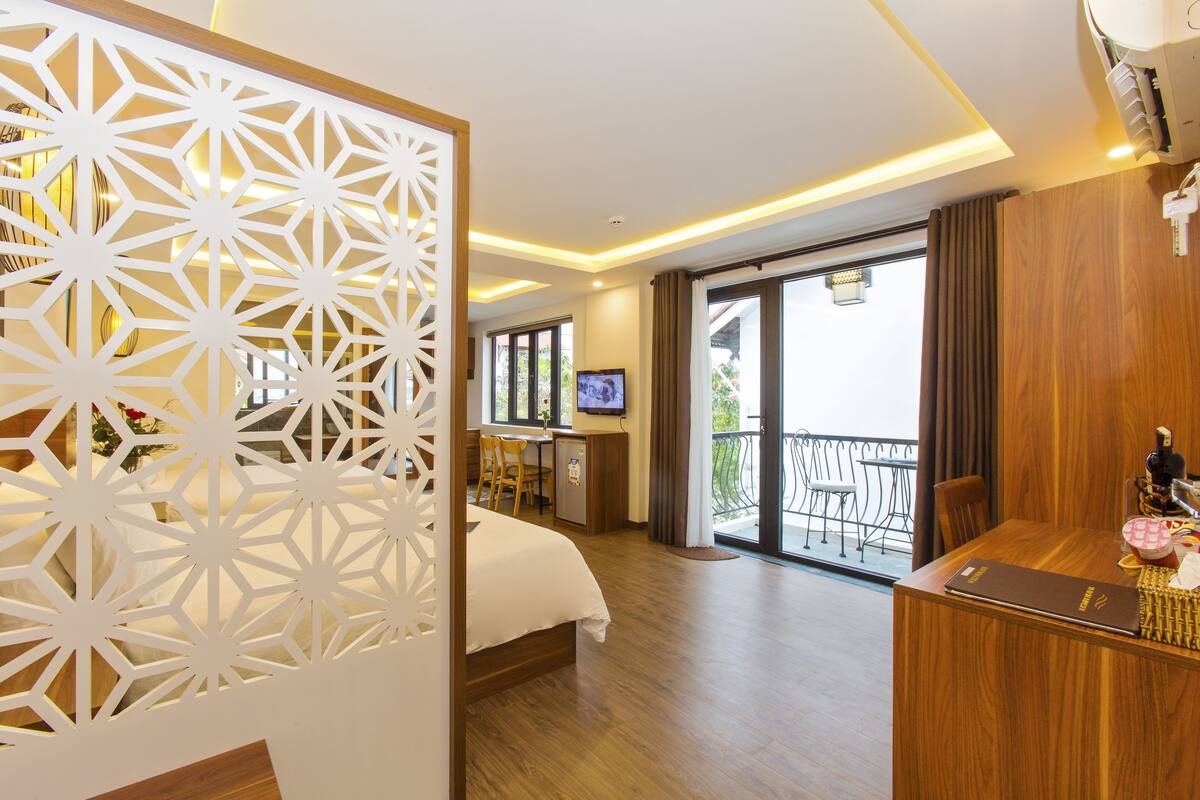 A hotel room with a bed, desk, and balcony.