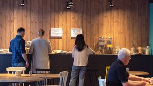A restaurant interior with wooden panel walls, tables, chairs, and a counter with a menu. - Marmota Hostel (Innsbruck)