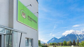 A hostel sign with a mountain backdrop. - Marmota Hostel (Innsbruck)