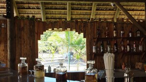 Eine Bar mit Holzvertäfelung, einem Reetdach und Blick auf Grün.