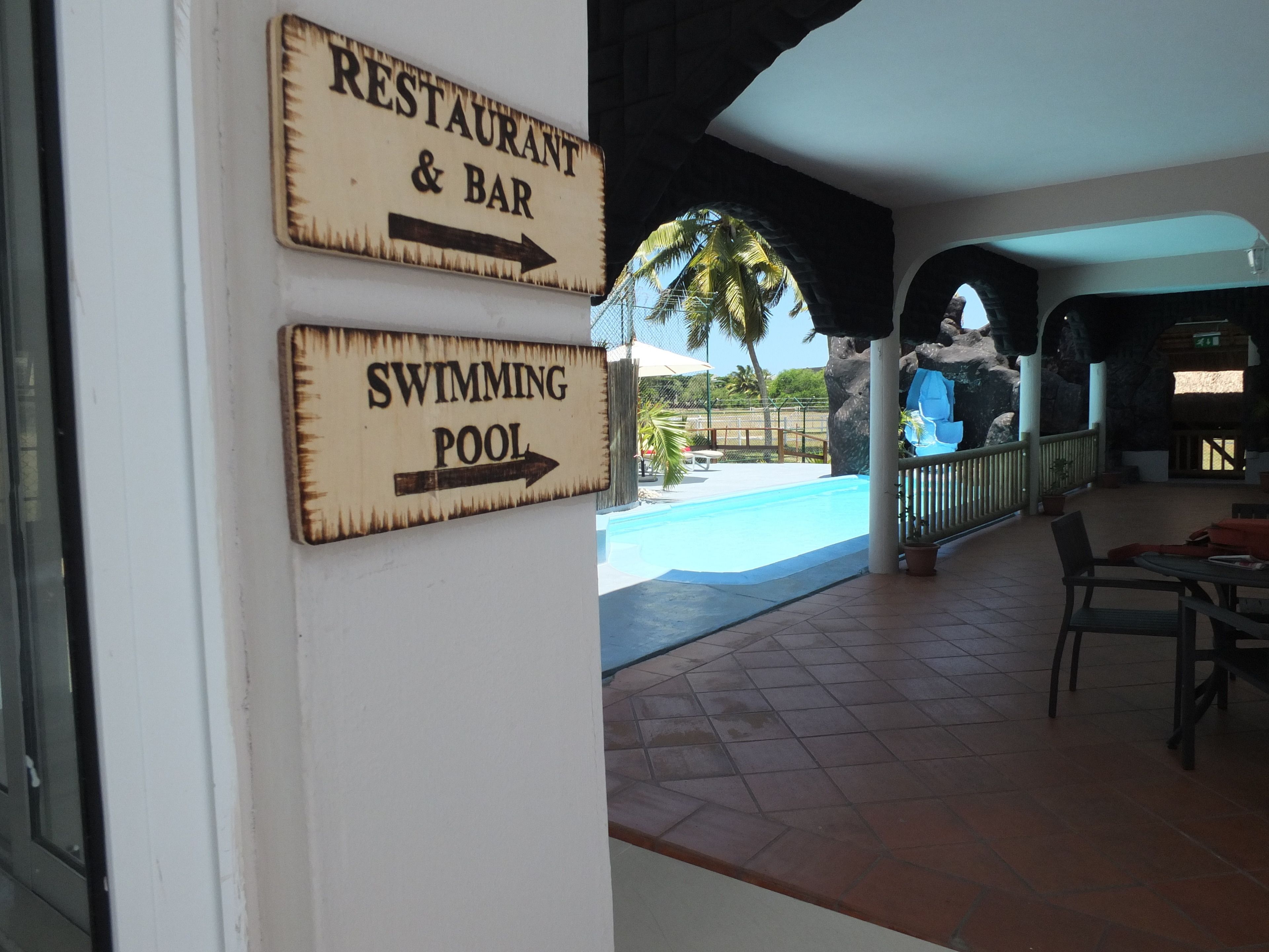 A restaurant and bar sign pointing to the right, and a swimming pool sign also pointing to the right.