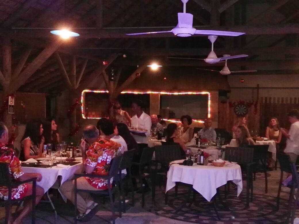 Ein Restaurant mit gedeckten Tischen, Deckenventilatoren und warmer, stimmungsvoller Beleuchtung.