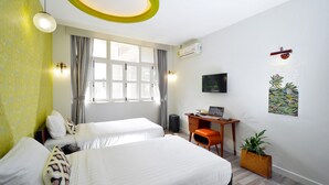 Habitación de hotel con dos camas, un escritorio, una silla, televisión, aire acondicionado y una ventana con cortinas.