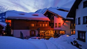 Un edificio cubierto de nieve con una entrada visible y una montaña al fondo.