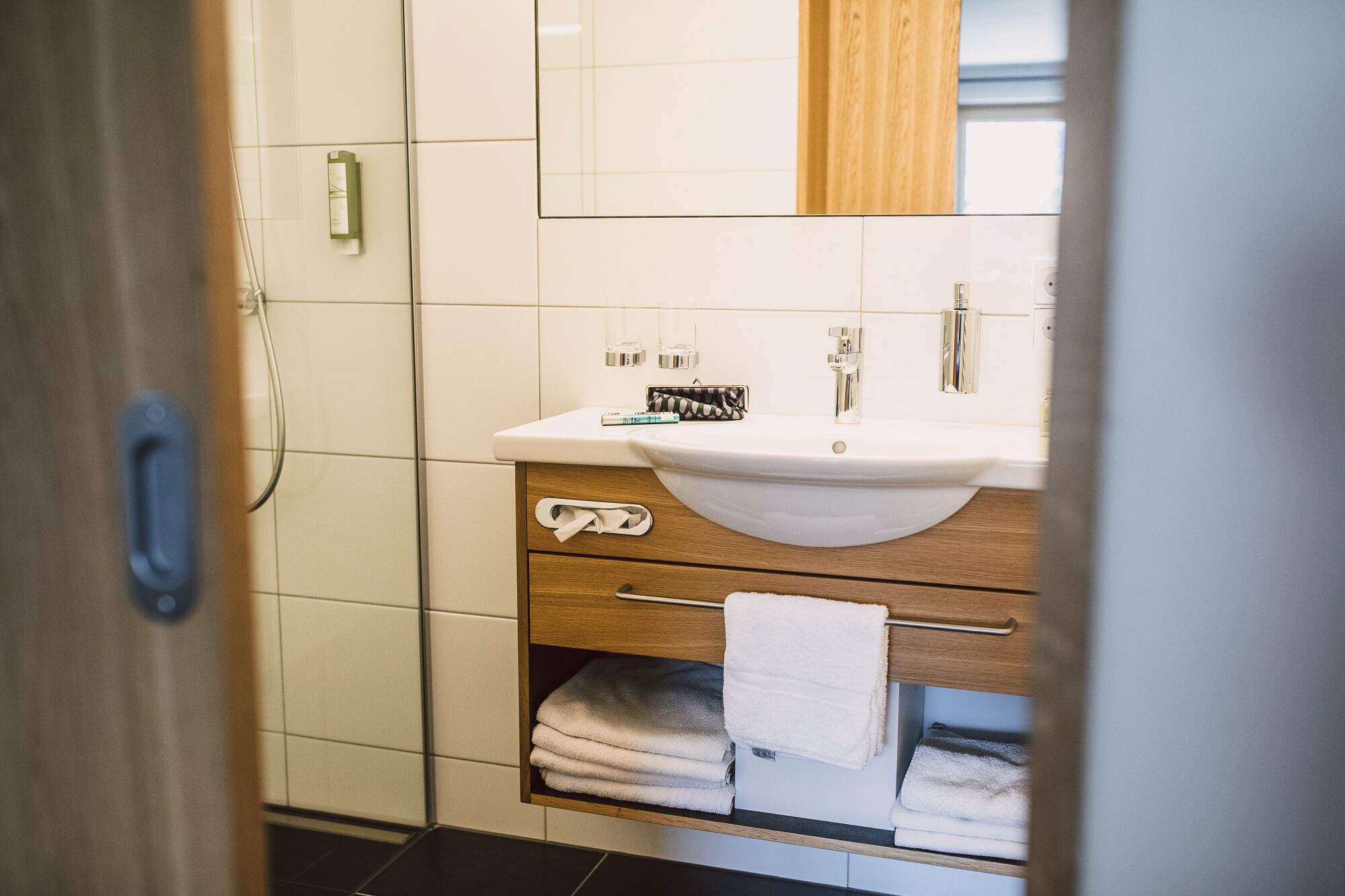 A bathroom with a white sink, wooden vanity, and a towel rack.