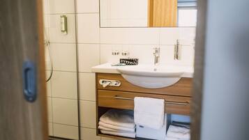 A bathroom with a white sink, wooden vanity, and a towel rack.