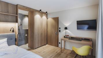 Una habitación de hotel moderna con cama, armario de madera, escritorio y televisor.