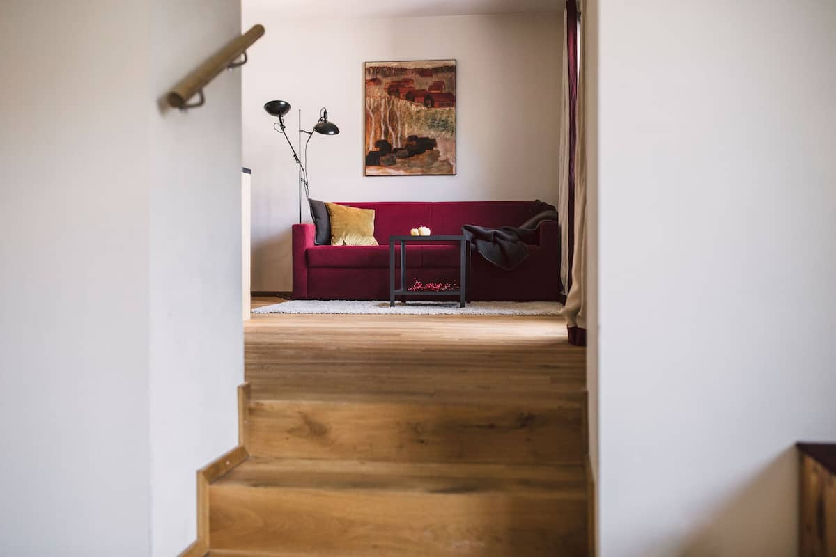 A staircase leading to a red sofa with a painting above it.