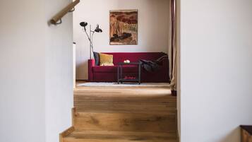 A staircase leading to a red sofa with a painting above it.