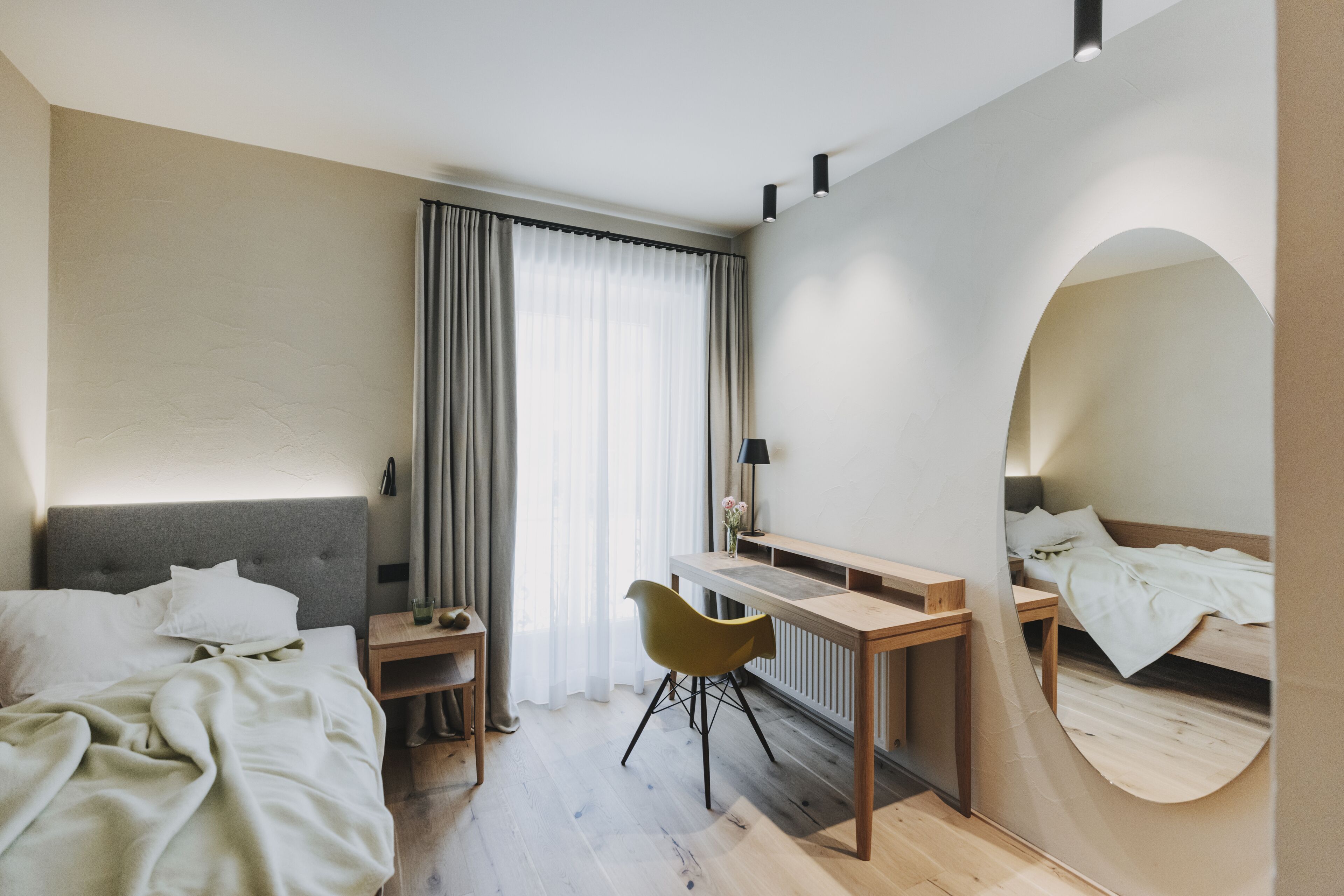 Een moderne hotelkamer met een bed, een bureau, een stoel en een spiegel.