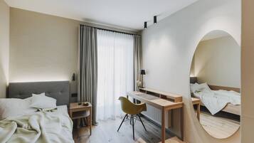 Een moderne hotelkamer met een bed, een bureau, een stoel en een spiegel.