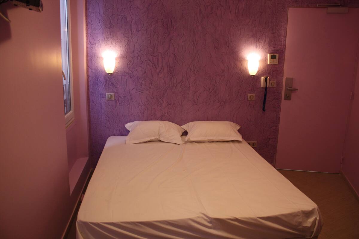 Una habitación con una cama, dos luces empotradas en la pared y una puerta.