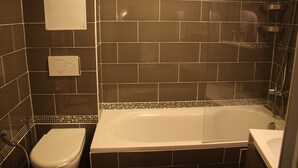A bathroom with a bathtub, toilet, and a shower area. - Arcotel (Cannes)