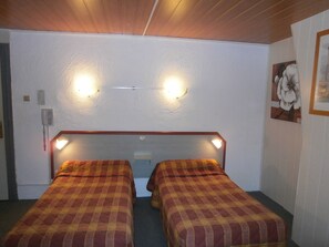 A room with two beds, a wooden ceiling, and a wall-mounted light fixture. - Hôtel Beauséjour (Rouen)