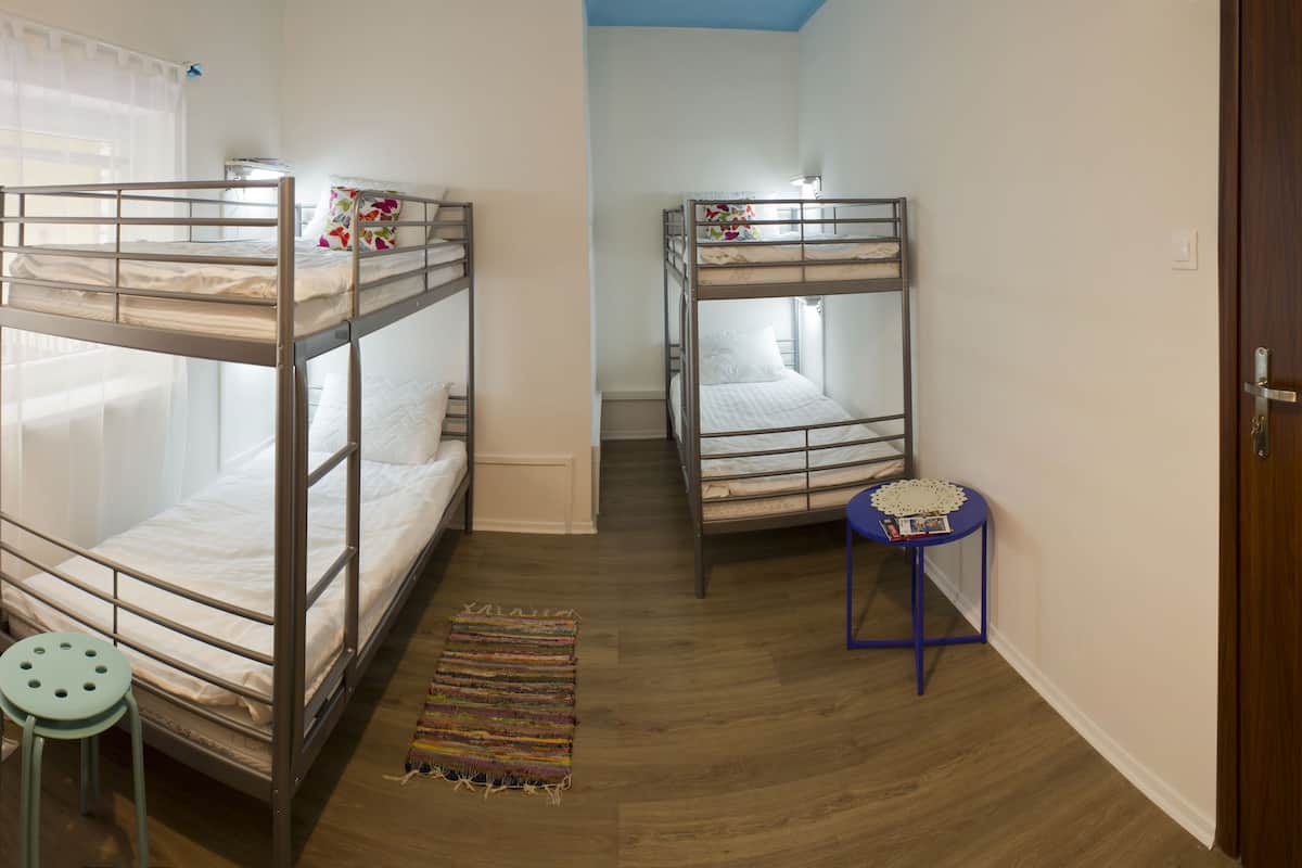 Una habitación con dos literas, una mesita redonda con un mantel de encaje y una puerta de madera.