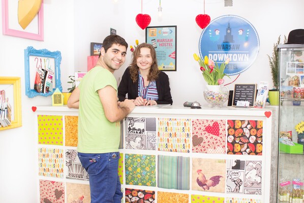 A reception desk with a variety of colorful fabric samples and a sign for Warsaw Downtown Hostel.